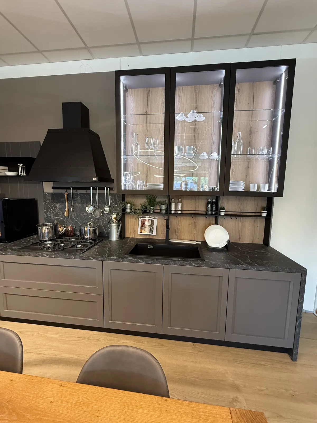 Cucina con vetrine illuminate e piano effetto marmo